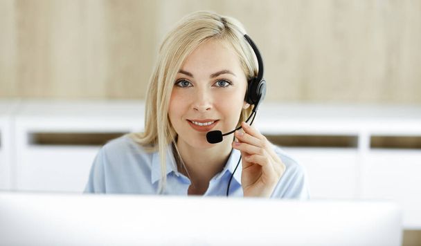 Blonde business woman sitting and communicated by headset in call center office. Concept of telesales business or home office occupation - Photo, Image