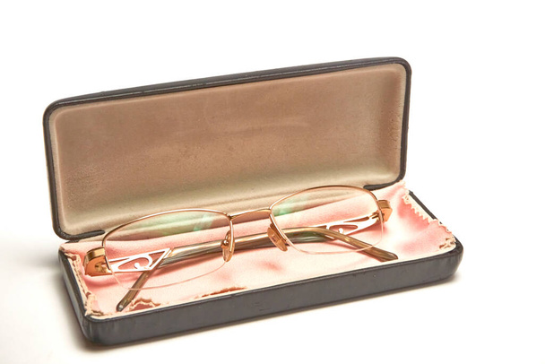 Γυαλιά σε χρυσά μεταλλικά πλαίσια σε θήκη σε ελαφρύ φόντο - Φωτογραφία, εικόνα