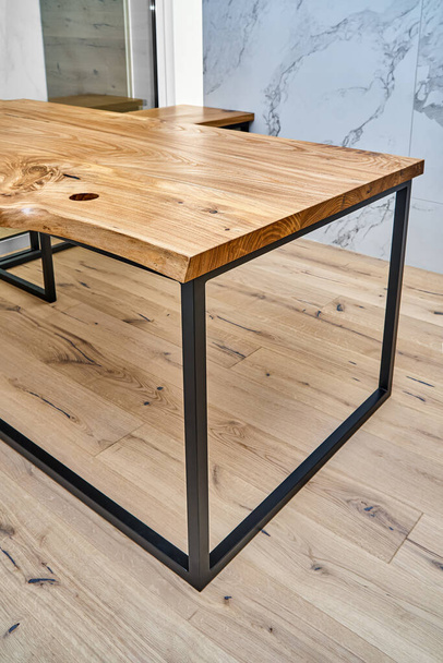Live edge elm gaming desk countertop with metal base in a modern home office. Fragment of the desk - Foto, imagen