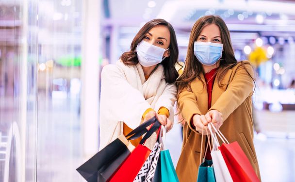 Two young girl friends in safety medical masks during shopping in the mall - Foto, immagini