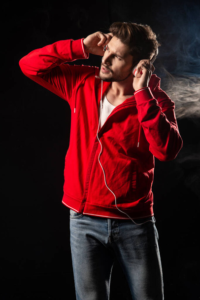 Strong man wear red hoodie over black background - Fotografie, Obrázek