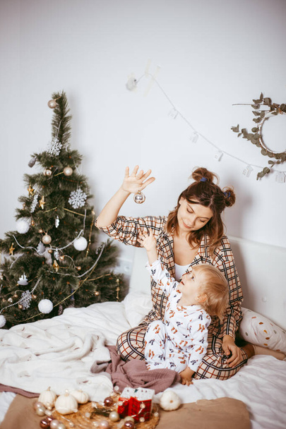 Portrait of a happy mother and a charming child at Christmas in a bright interior - Фото, изображение