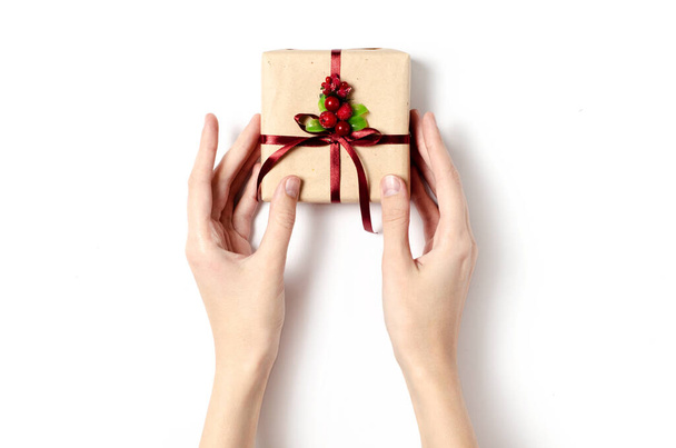 Frau hält das Weihnachtsgeschenk in ihren Händen auf weißem Hintergrund, isolierte weibliche Hände und Weihnachtsgeschenk - Foto, Bild