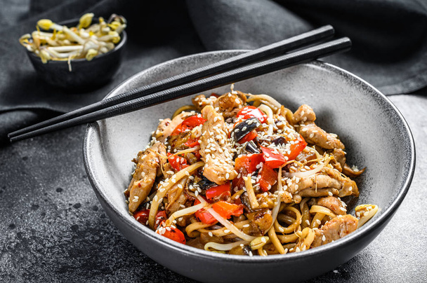 Udon stir-fry noodles with chicken meat and sesame. Black background. Top view. - Foto, afbeelding