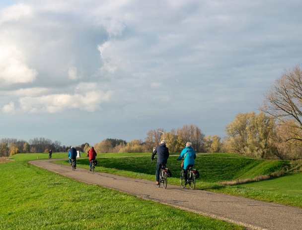 Hollandalılar Weurt ve Beuningen arasında Gelderland 'de bir hendekte bisiklet sürerken, fotoğraf sonbaharda güneşli bir günde çekildi. - Fotoğraf, Görsel