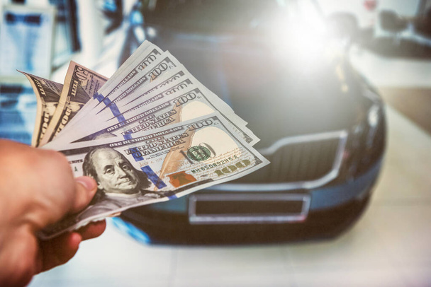  Un homme avec 100 dollars de billets de banque près de la voiture. Acheter ou louer une nouvelle voiture. Concept de financement - Photo, image