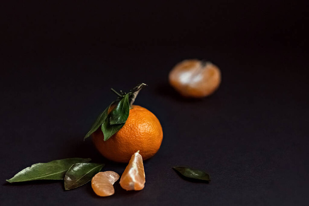 Fruta fresca de mandarina con hojas verdes aisladas sobre un fondo negro - Foto, Imagen