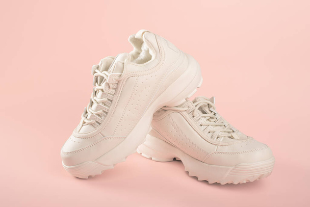 White sneakers on light pink background. Pair of trendy women's sneakers on pastel background. sports shoes concept - Foto, Imagem