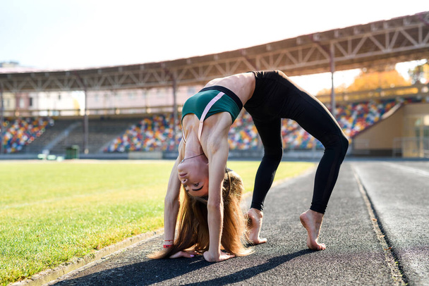 Young sportive woman making morning exercises outdoors on the stadium - Photo, Image