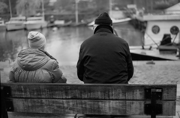 Пожилая пара, повернувшись спиной, сидит на скамейке и смотрит - Фото, изображение