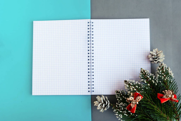 Nyílt mockup notebook és karácsonyfa ágak színes háttér. Újévi üdvözlőlap sablonja. Boldog karácsonyt és boldog új évet! - Fotó, kép