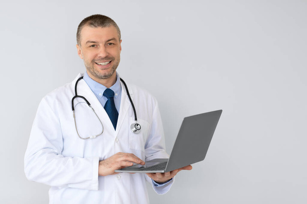 Portrait of male medical practitioner holding laptop - Foto, afbeelding