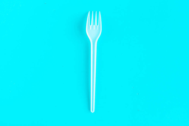 Kunststof vork op blauwe achtergrond, bovenaanzicht - Foto, afbeelding