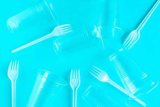 Пластикові чашки та вилки на синьому фоні, вид зверху
 - Фото, зображення
