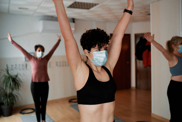 Ομάδα γυναικών που ασκούν ασκήσεις Pilates στην τάξη με μάσκες - Φωτογραφία, εικόνα