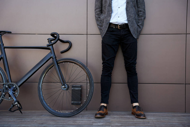 Τραβηγμένο πλάνο του κομψού μεσήλικα άντρα που στέκεται έξω με το ποδήλατό του - Φωτογραφία, εικόνα