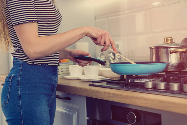 Happy young woman is preparing the diner in the kitchen. Healthy female lifestyle. Diet - 写真・画像