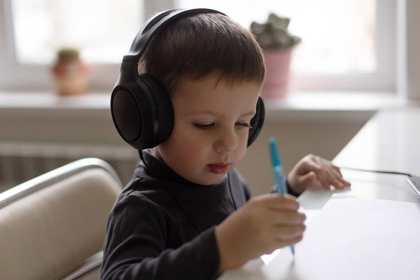 the Beautiful little boy at home, headphones, pen - Foto, immagini