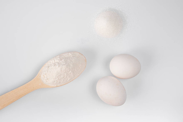 ingredients for making pasta, pizza, cake, cookies. flour in a wooden spoon, sugar, eggs on a white background. products for cooking at home. healthy foods - Photo, image