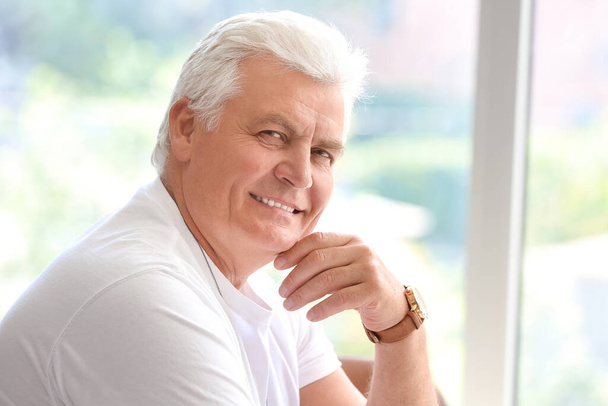 Portret van een oudere man bij het raam thuis - Foto, afbeelding