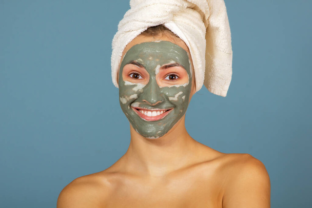 Beautiful cheerful teen girl with dark facial clay mask. Beauty treatments, body care - Valokuva, kuva