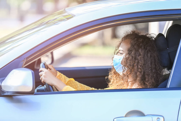Αφροαμερικανή γυναίκα που φοράει ιατρική μάσκα ενώ οδηγεί αυτοκίνητο - Φωτογραφία, εικόνα