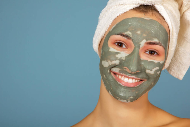 Beautiful happy smiling teen girl with dark facial clay mask. Beauty treatments, body care - Foto, Bild