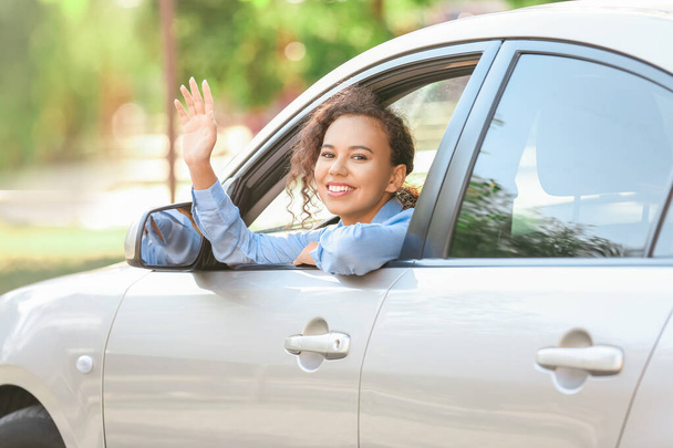 Happy African-American woman looking out of car window - Фото, изображение