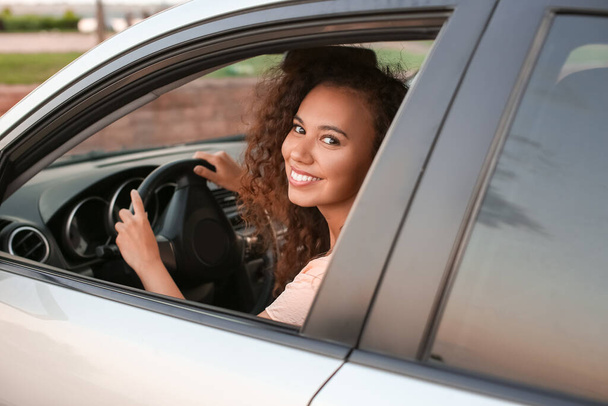 若いアフリカ系アメリカ人女性が車を運転する - 写真・画像