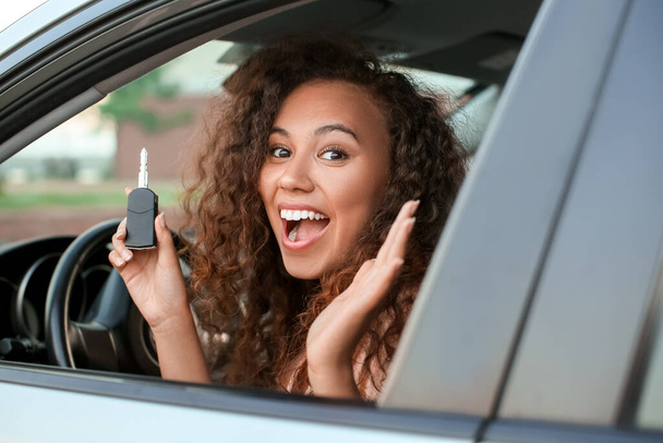 Happy African-American woman with key sitting in new car - Valokuva, kuva