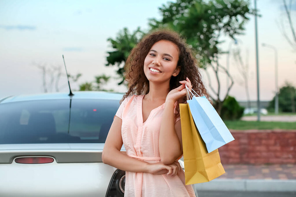 Mladá afroamerická žena s nákupními taškami v blízkosti auta venku - Fotografie, Obrázek