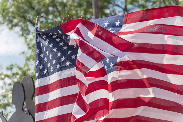 Levant les yeux en agitant des drapeaux américains avec un fond d'arbres verts lors d'une manifestation pacifique près de Dallas, Texas, Amérique. Marche fièrement, rassemblement, patriote, concept de protestation - Photo, image