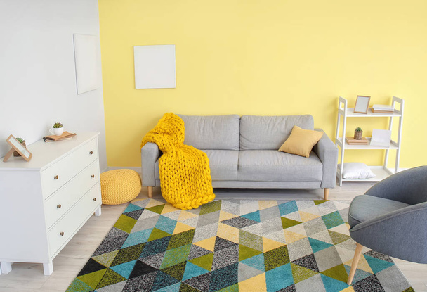 Interno di camera moderna con divano e plaid lavorato a maglia - Foto, immagini