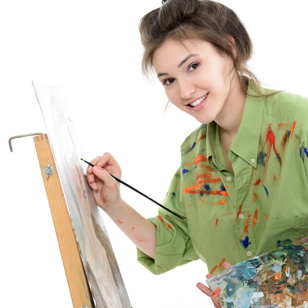 Attractive teen girl painter drawing portrait with oil paints, professional painter at work over white background. Studio portrait of young woman artist - Foto, Imagen