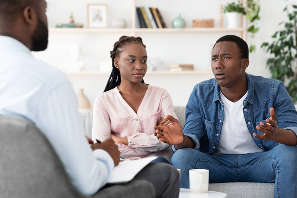 Emotionele zwarte man praten met familie adviseur bij echtelijke therapie sessie - Foto, afbeelding