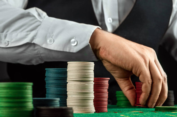 Male hands croupier in a casino and playing chips on a green cloth close-up. Casino concept, gambling, blackjack - Valokuva, kuva