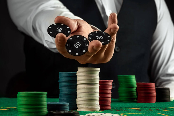 Male hands croupier in a casino and playing chips on a green cloth close-up. Casino concept, gambling, blackjack - Фото, изображение