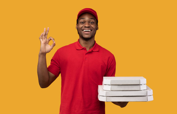 Black delivery man holding pizza boxes, showing okay gesture - Photo, Image