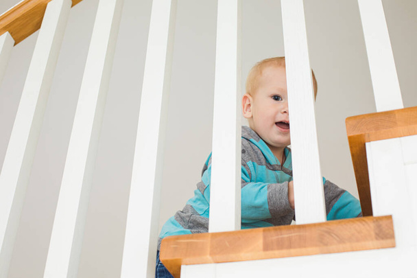 Ahşap merdivenlerde saklambaç oynayan neşeli çocuk - Fotoğraf, Görsel