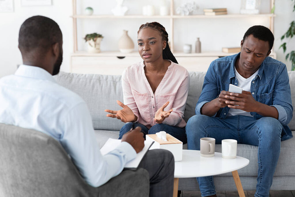 Tyytymätön musta nainen syyttää aviomies psykologi konsultointi, valittavat älypuhelin riippuvuus - Valokuva, kuva