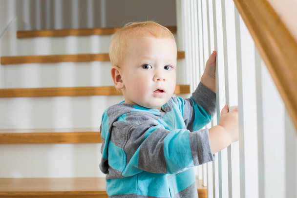 The baby carefully goes down the stairs at home - 写真・画像