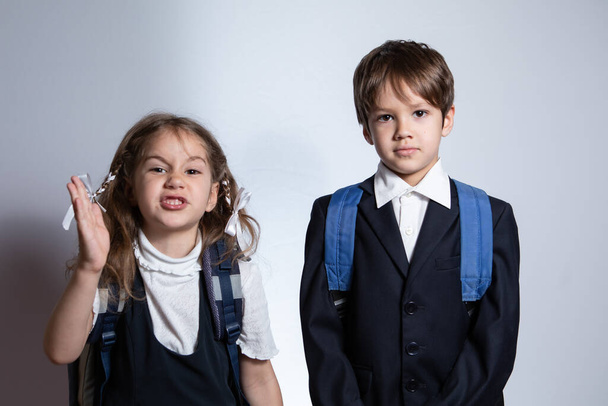 The boy and girl are now looking at the camera. They are wearing school uniforms.  - Foto, imagen