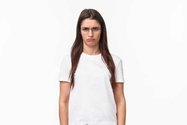 Waist-up portrait of sulking young offended gloomy girl, look with contempt camera, squinting blame person for spoiling her holiday, frowning grumpy, standing white background - Фото, зображення