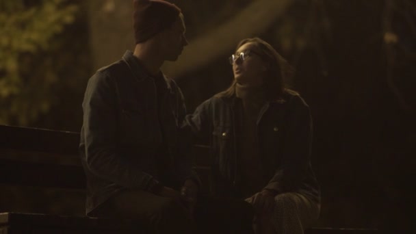 若いカップルの終わりは夜の公園のベンチに座っている - 映像、動画