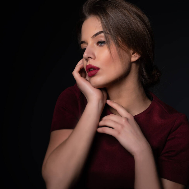 Portrait of attractive young woman over gray background. Amazing girl with perfect makeup wearing elegant deep red dress. Beauty and fashion - Fotó, kép