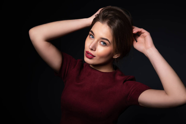 Portrait of attractive young woman over gray background. Amazing girl with perfect makeup wearing elegant deep red dress. Beauty and fashion - Fotó, kép