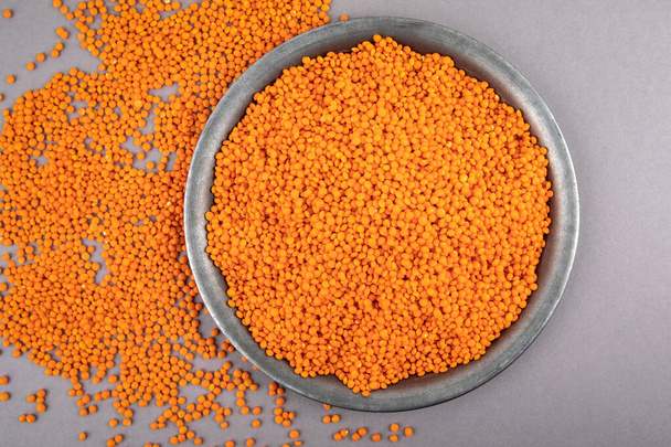 Red lentils in a metal plate on a gray table - Photo, Image