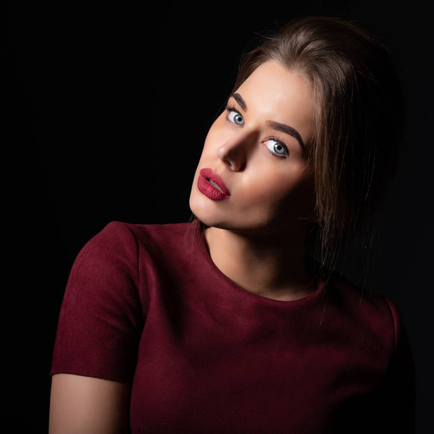 Portrait of attractive young woman over black background. Amazing girl with perfect makeup wearing elegant deep red dress. Beauty and fashion - Fotoğraf, Görsel