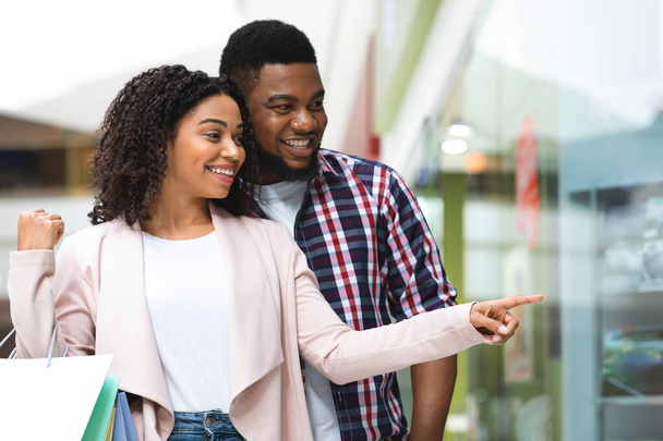 Давай купим это. Happy Black Woman Shopping with Boyfriend, Pointing At Showcase - Фото, изображение