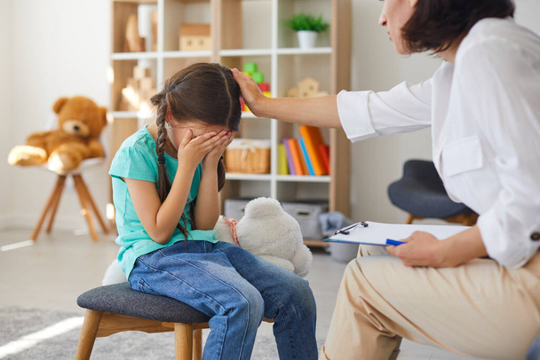 Little girl crying in psychotherapists office sharing problems and concerns and seeking help - Foto, imagen